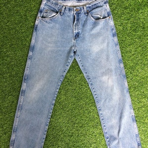 May include: Light blue denim jeans with a straight leg fit and a frayed hem. The jeans have a classic five-pocket design and a button fly.