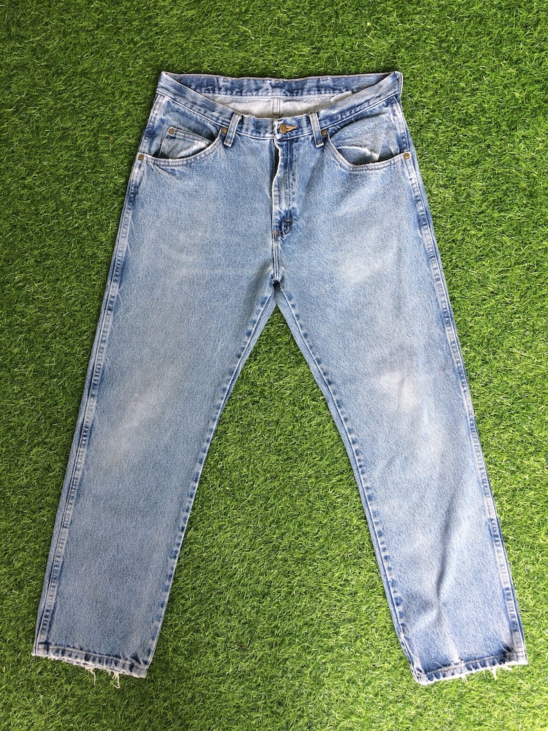 May include: Light blue denim jeans with a straight leg fit and a frayed hem. The jeans have a classic five-pocket design and a button fly.