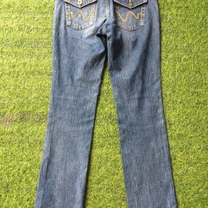 May include: Blue denim jeans with a classic five-pocket design. Features include decorative stitching on the back pockets and a leather patch with the brand name. The jeans have a straight leg cut.