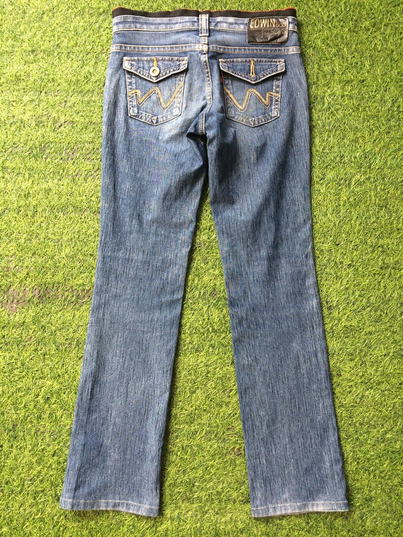 May include: Blue denim jeans with a classic five-pocket design. Features include decorative stitching on the back pockets and a leather patch with the brand name. The jeans have a straight leg cut.