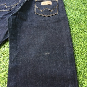 Peut inclure: Un jean en denim bleu fonc&eacute; avec un &eacute;cusson en cuir brun sur la poche arri&egrave;re qui dit "Wrangler".