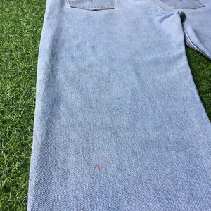 May include: Light blue denim jeans with a faded look and visible wear. The jeans have a straight leg and a classic five-pocket style.