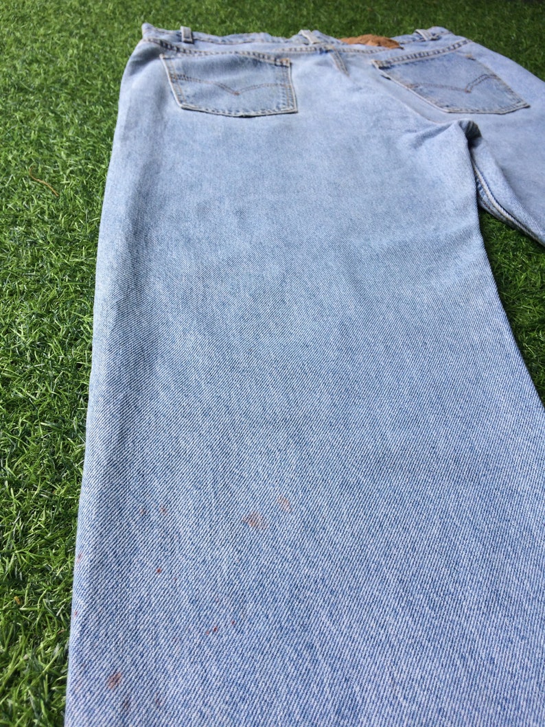 May include: Light blue denim jeans with a faded look and visible wear. The jeans have a straight leg and a classic five-pocket style.