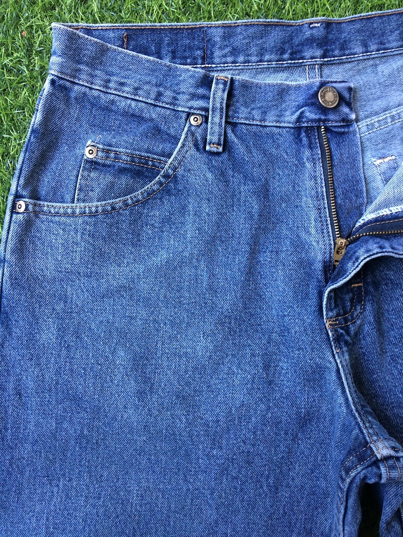 May include: A pair of blue denim jeans with a zip fly and a button fastening. The jeans have a classic five-pocket style with a front pocket on the right side and two back pockets.