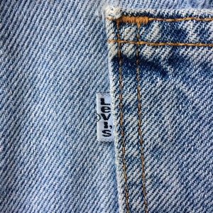 May include: Close-up of a blue denim pocket with a white Levi's label sewn on the side.