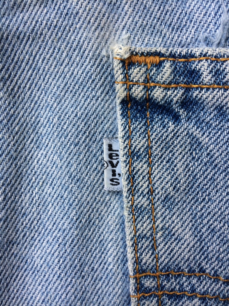 May include: Close-up of a blue denim pocket with a white Levi's label sewn on the side.