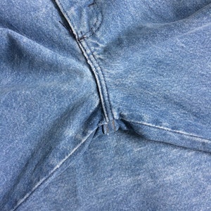 May include: Close-up of a pair of blue denim jeans with a seam running down the center.