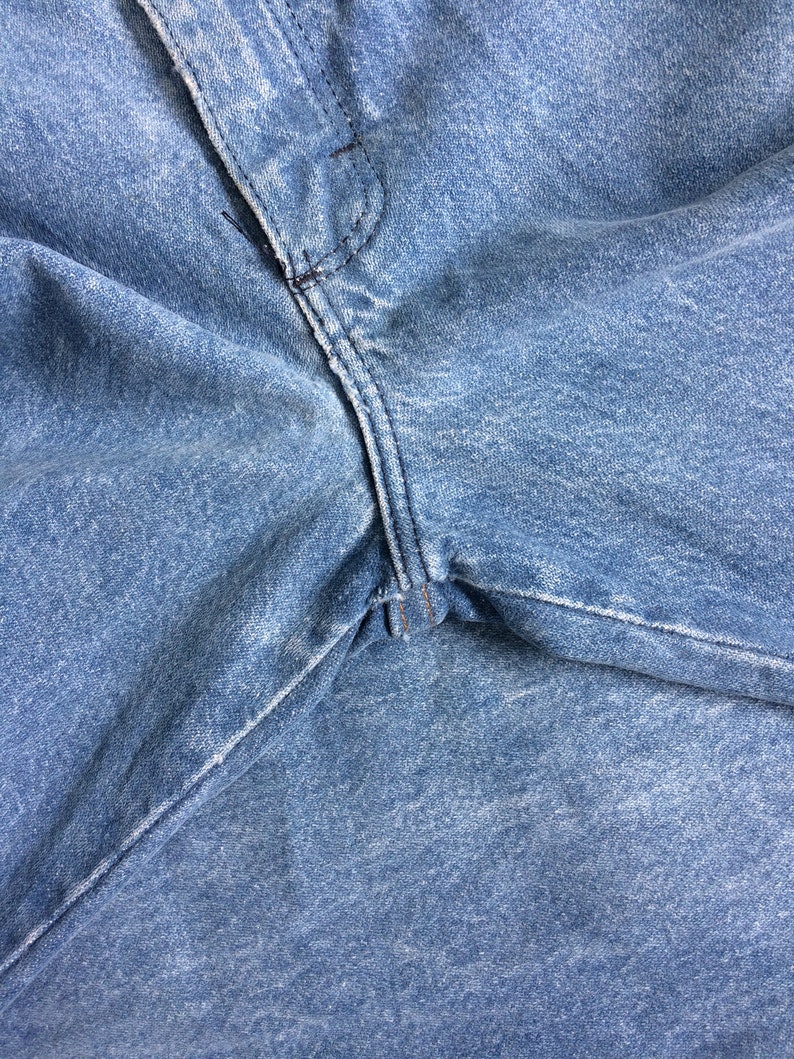 May include: Close-up of a pair of blue denim jeans with a seam running down the center.