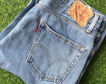 May include: A pair of light blue denim jeans with a back pocket and a Levi's label. The label is brown with white text and says "Levi Strauss & Co.  Original  Rivet  Denim  501  554 33 29".