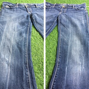 Op de afbeelding: Een paar blauwe denim jeans met een vervaagde look en stiksels. De jeans heeft een rechte pijp en een klassiek ontwerp met vijf zakken.