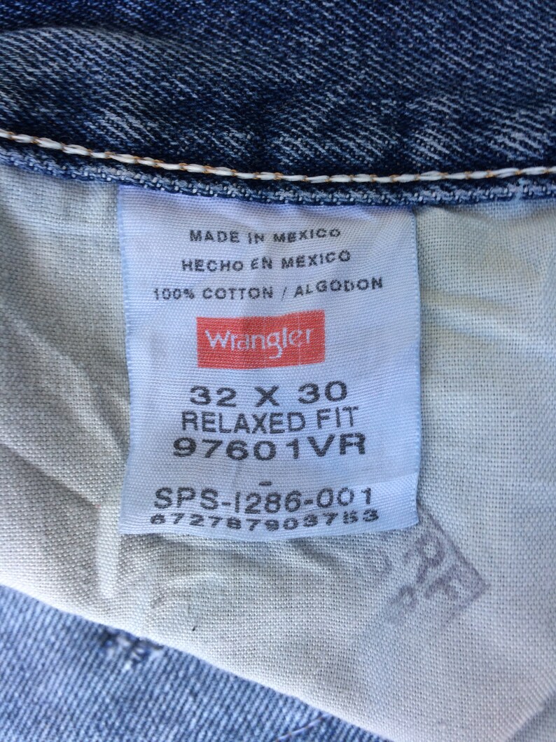 May include: A white tag with black text and a red Wrangler logo. The tag says "Made in Mexico, Hecho en Mexico, 100% Cotton/Algodon". Below the logo, the tag says "32 X 30 Relaxed Fit 97601VR SPS-1286-001 6727879037153".