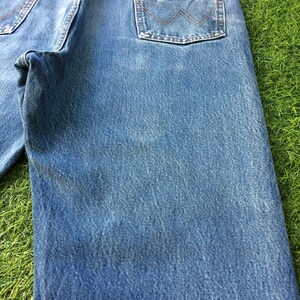 May include: A pair of blue denim jeans with a brown leather patch on the back pocket that says "Wrangler".