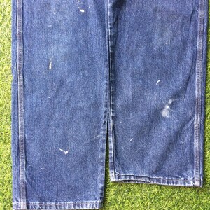 May include: A pair of blue denim carpenter jeans with visible wear and tear. The jeans have a straight leg and are made of a durable cotton blend.
