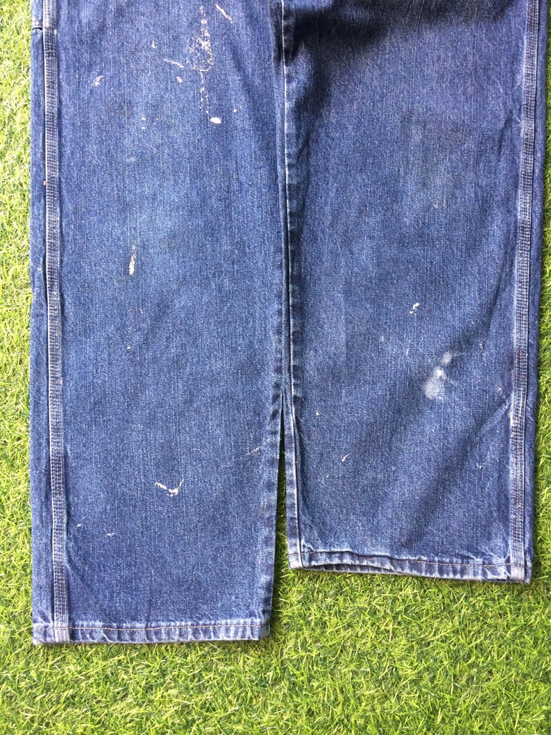 May include: A pair of blue denim carpenter jeans with visible wear and tear. The jeans have a straight leg and are made of a durable cotton blend.