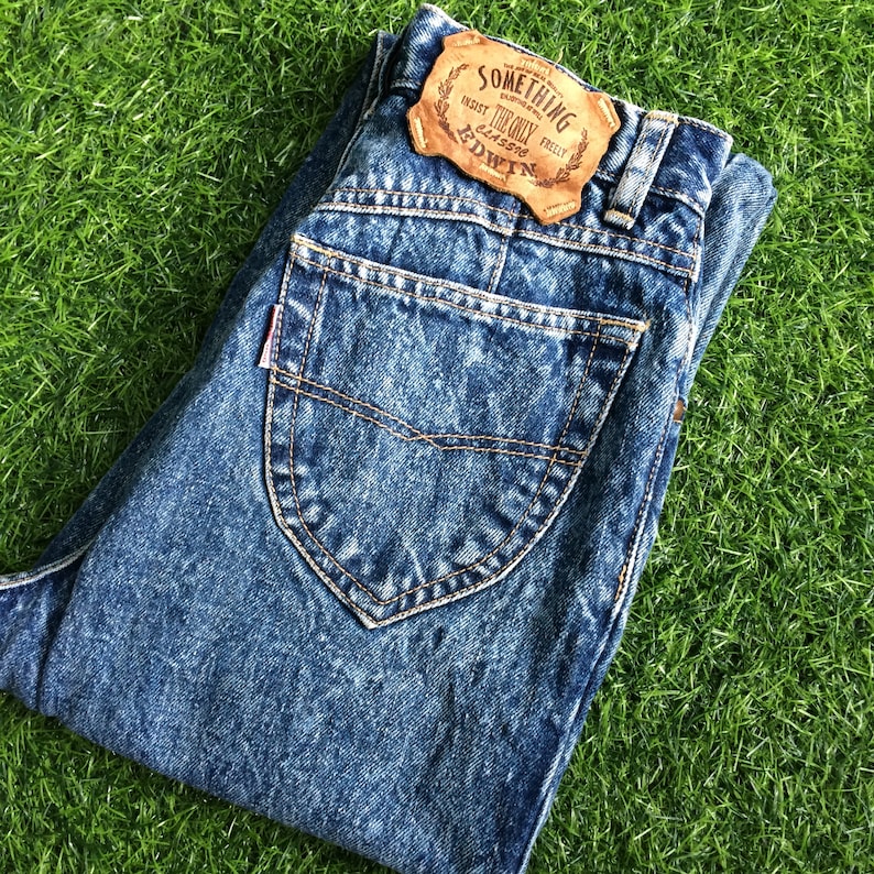May include: A pair of blue denim jeans with a brown leather patch that says "Something Endorsed By The Only Genuine Edwin".