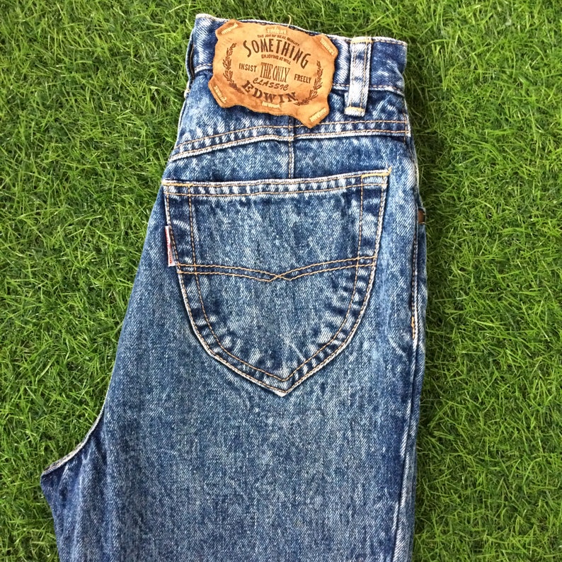 May include: Light blue denim jeans with a brown leather patch that says "Something The Only Classic Edwin".