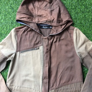May include: A brown and beige hooded jacket with a zipper closure and a patch pocket on the left side. The jacket has the text "Blue Pearl" on the label.