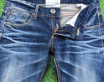 May include: A pair of blue denim jeans with a zipper fly and button closure. The jeans have a faded and distressed look with visible stitching. The label on the jeans reads "Edwin Jeans" and "Made in Japan".