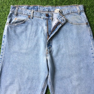 May include: Light blue denim jeans with a zipper fly and a button closure. The jeans have a classic five-pocket style.