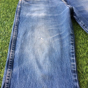May include: A pair of blue denim jeans with a faded look and a small hole on the left leg.