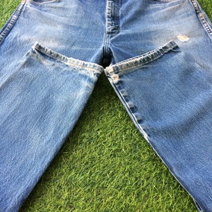 May include: A pair of light blue denim jeans with a faded look. The jeans have a straight leg and a classic five-pocket design.