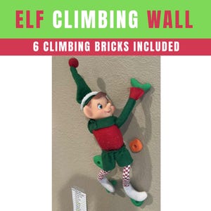 May include: An elf doll wearing a green hat, shirt, and shorts, with red accents, is attached to a wall with green climbing holds. The text "ELF CLIMBING WALL" and "6 CLIMBING BRICKS INCLUDED" are displayed above the elf.