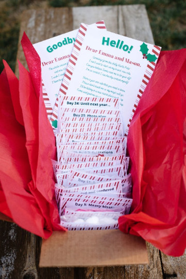 K&ouml;nnte beinhalten: Eine festliche Geschenkbox mit rotem Seidenpapier, die Karten und kleine P&auml;ckchen enth&auml;lt. Die Karten sagen "Hallo!" und "Auf Wiedersehen" mit Zuckerstangenstreifen. Die P&auml;ckchen sind mit Tagen und S&auml;tzen wie "schmutzige K&uuml;sse" beschriftet.