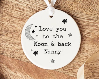 Könnte beinhalten: Weißer Keramik-Anhänger mit einem schwarz-weißen Mond- und Sternen-Design. Der Anhänger trägt die Aufschrift "Love you to the Moon & back Nanny".