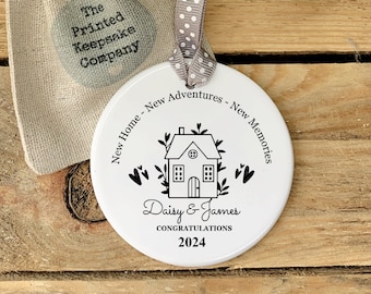 Może przedstawiać: Biała ceramiczna ozdoba z czarnym rysunkiem domu, liści i serc. Tekst głosi "New Home - New Adventures - New Memories", "Daisy & James", "Congratulations" i "2024".