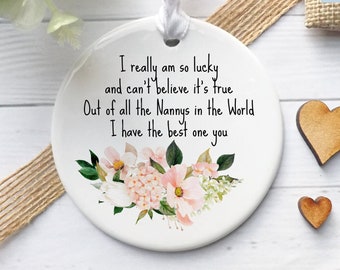 May include: A white ceramic ornament with a floral design and the text "I really am so lucky and can't believe it's true... I have the best one you." A white ribbon is attached for hanging. Two small wooden hearts are next to the ornament.