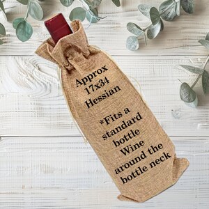 May include: A tan Hessian wine bottle bag with a drawstring closure. The bag is approximately 43x86 cm and is designed to fit a standard wine bottle. Text on the bag reads "Approx 17x34 Hessian" and "Fits a standard bottle Wine around the bottle neck."