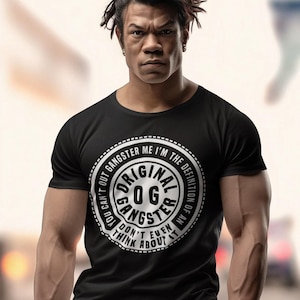 May include: Black t-shirt with a white circle graphic that says "You can't out gangster me I'm the definition of an Original OG Gangster Don't even think about it."