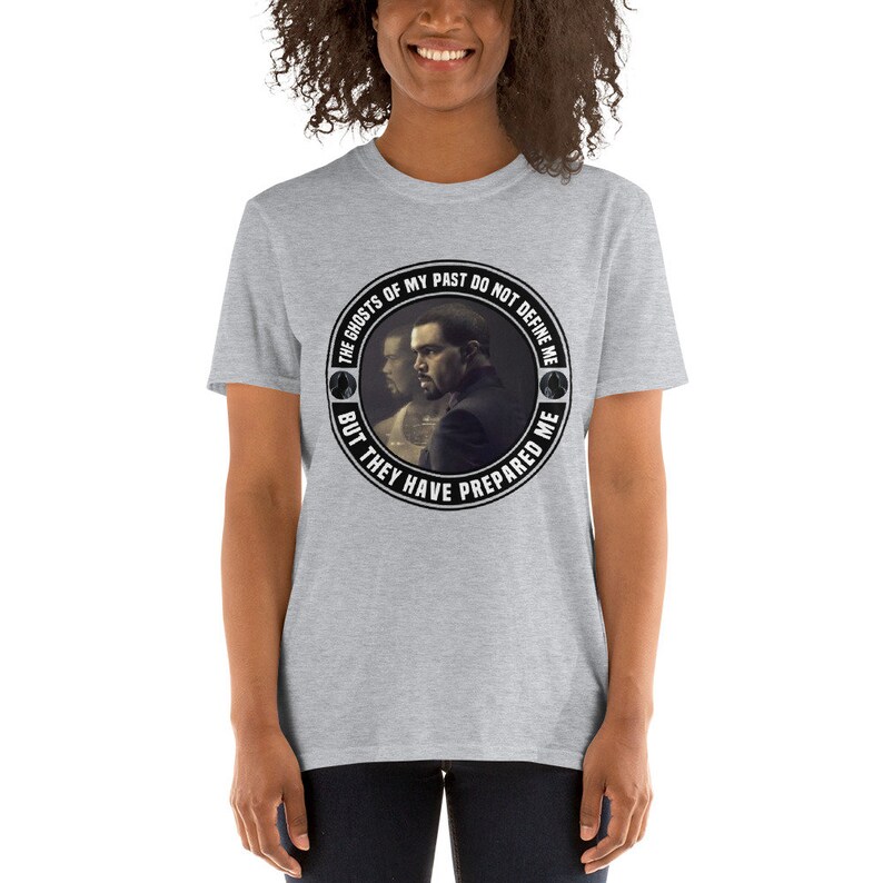May include: Gray t-shirt with a black and white circular graphic featuring a man's face and the text "The ghosts of my past do not define me but they have prepared me."