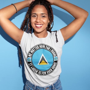 May include: A white t-shirt with a black circle design featuring the flag of Saint Lucia and the text "No matter how far I roam, St. Lucia is for ever home."