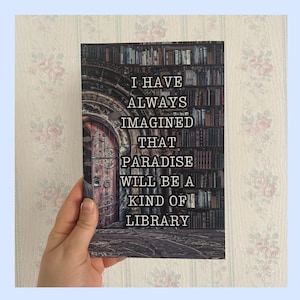 Könnte beinhalten: Ein Buch mit einem Zitat darüber, dass das Paradies eine Bibliothek ist. Das Zitat lautet "Ich habe mir immer vorgestellt, dass das Paradies eine Art Bibliothek sein wird". Das Buchcover zeigt eine dunkle, verzierte Tür mit einem Bücherregal im Hintergrund.