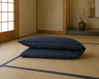 May include: Two rectangular pillows stacked on top of each other, featuring a dark navy blue fabric base with a small, repeating white floral pattern. The pillows have a soft, filled appearance and are positioned horizontally in the center.