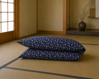 May include: Two rectangular pillows stacked on top of each other, featuring a dark navy blue fabric base covered in a dense, repeating pattern of small white, light pink, and light blue flowers across the entire surface of both cushions.