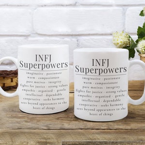 May include: Two white ceramic mugs with black text that reads "INFJ Superpowers" and lists personality traits associated with the INFJ personality type.