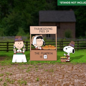 Könnte beinhalten: Eine Zeichentrickszene mit Charlie Brown, Lucy und Snoopy aus der Peanuts-Bande. Charlie Brown sitzt an einem Tisch, Lucy verkauft Kuchen und Snoopy hält einen Korb. Ein Schild lautet "Thanksgiving Pies 5¢" und "The Pumpkin is In."
