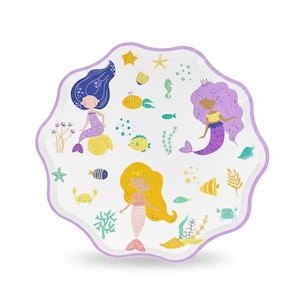 May include: A scalloped-edge paper plate with a white background featuring a pattern of three mermaids with blue, purple, and yellow hair, surrounded by illustrations of yellow shells, green seaweed, small colorful fish, and crabs.