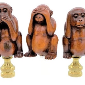 May include: Three brown monkey figurines in the "See no evil, Hear no evil, Speak no evil" pose. Each monkey is seated on a gold-colored, textured base. The monkeys have detailed facial features and are made of a wood-like material.