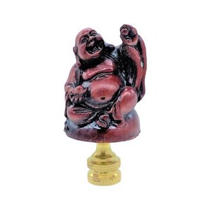 May include: A lamp finial featuring a laughing Buddha figure in shades of red and brown. The Buddha is seated and has a joyful expression. The finial is mounted on a gold-colored base.