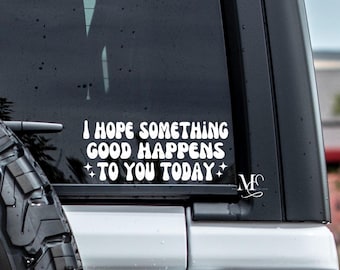 May include: White vinyl decal with the text "I HOPE SOMETHING GOOD HAPPENS TO YOU TODAY" in a retro font, with star accents. The decal is affixed to a vehicle window.