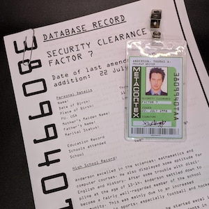 Peut inclure: Un gros plan sur un dossier de sécurité avec le texte "DATABASE RECORD" et "SECURITY CLEARANCE FACTOR 7". Le dossier comprend des informations personnelles et un relevé de notes du lycée. Un badge de sécurité avec le texte "METACORTEX" et "SECURITY CLEARANCE FACTOR?" est attaché au dossier.