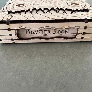 May include: A wooden box with a carved monster face on the front. The box is labeled "Monster Book".