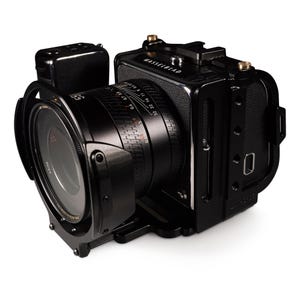 Könnte beinhalten: Schwarze Hasselblad-Kamera mit Objektiv und Zubehör. Das Kameragehäuse ist rechteckig mit Objektiv und Sucher. Das Objektiv hat Messmarkierungen. Die Kamera steht vor weißem Hintergrund.