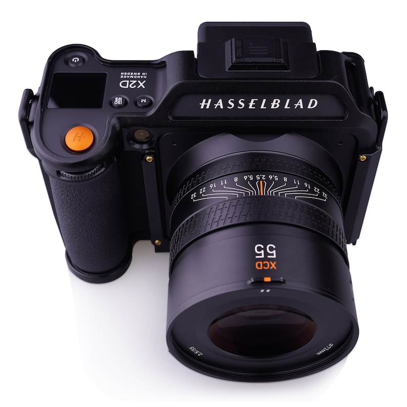 K&ouml;nnte beinhalten: Eine schwarze Hasselblad X2D Kamera mit einem schwarzen XCD 55mm Objektiv. Die Kamera verf&uuml;gt &uuml;ber ein digitales Display und verschiedene Kn&ouml;pfe und Drehregler. Das Objektiv hat eine Tiefensch&auml;rfenskala und einen Blendenring.