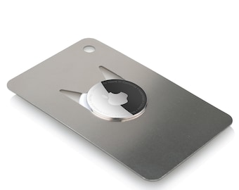 Könnte beinhalten: Ein silberner Schlüsselanhänger aus Metall mit einem schwarz-weißen Apple-Logo in der Mitte. Der Schlüsselanhänger hat einen Flaschenöffner und eine Schlaufe zum Anbringen von Schlüsseln.