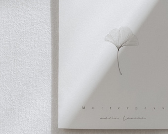 Puede incluir: Una tarjeta blanca con una ilustración en blanco y negro de una hoja de ginkgo. El texto "Mutterpass" y "marie louise" está escrito en tinta negra.