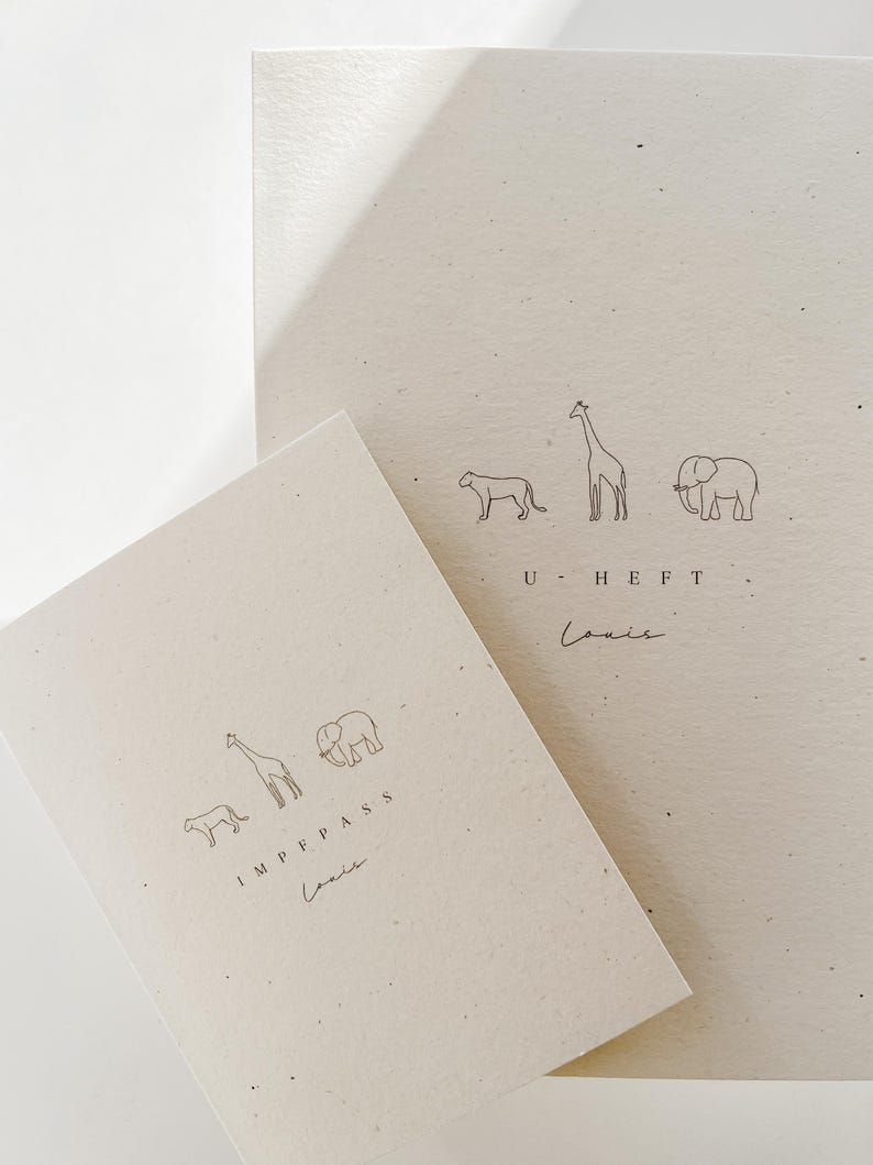 May include: Two off-white paper covers with speckled texture. The smaller cover features line drawings of a lion, giraffe, and elephant above the text IMPFPASS and the name Louis. The larger cover features the same animals above U-HEFT and Louis.